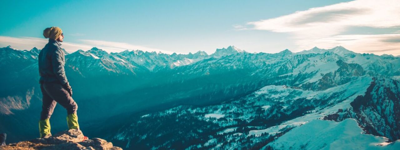 Person står på en bergstopp.